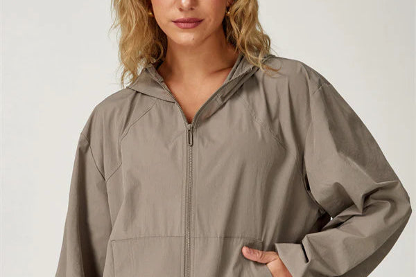 Woman wearing a beige zip-up jacket and shorts set on a plain background
