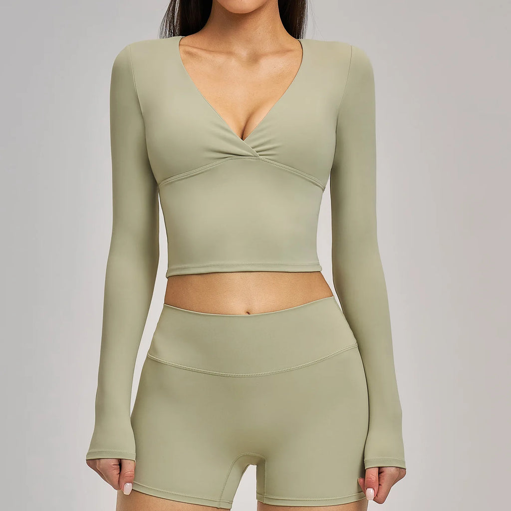 Person wearing a green long-sleeve top and shorts set on a gray background