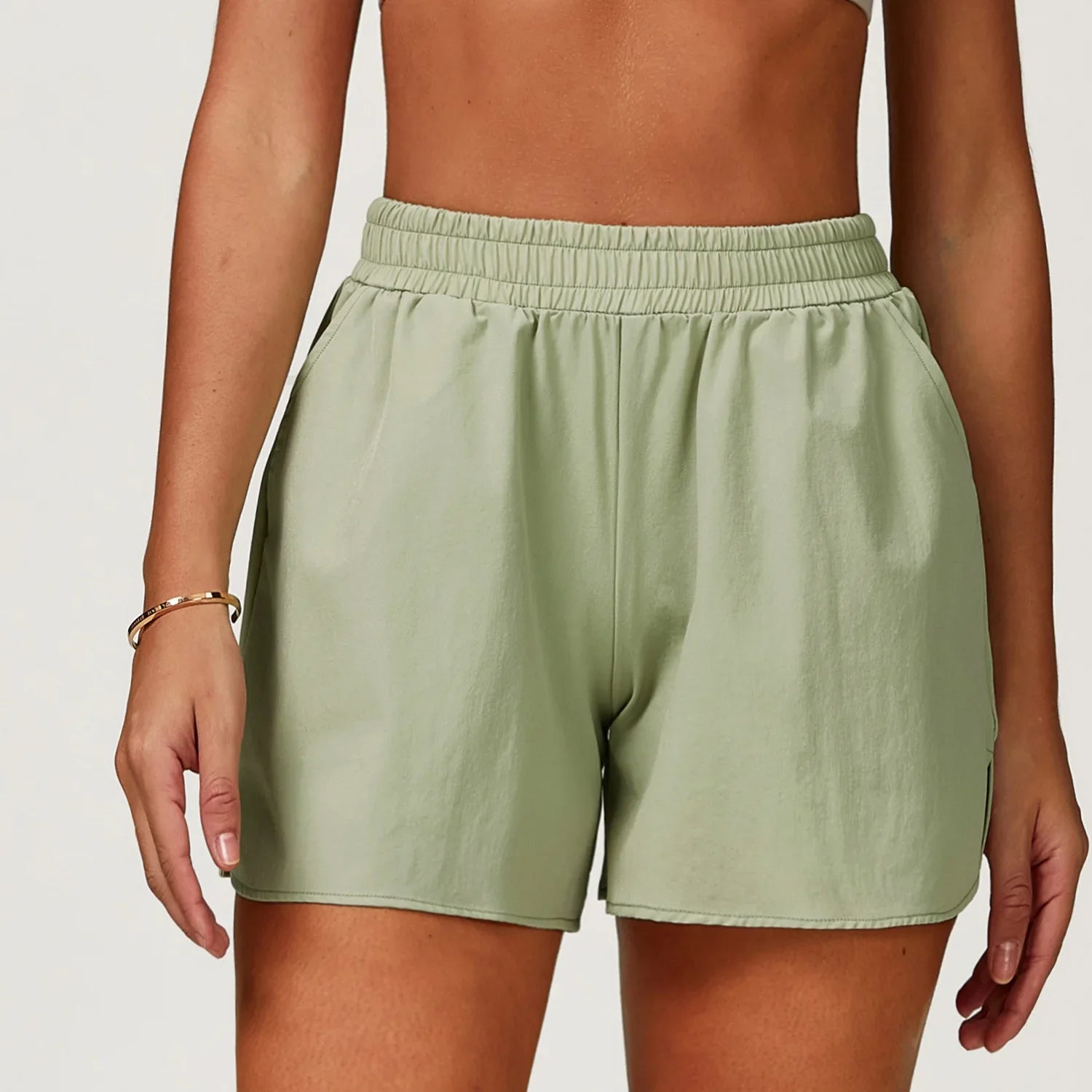 Person wearing light green shorts on a plain background