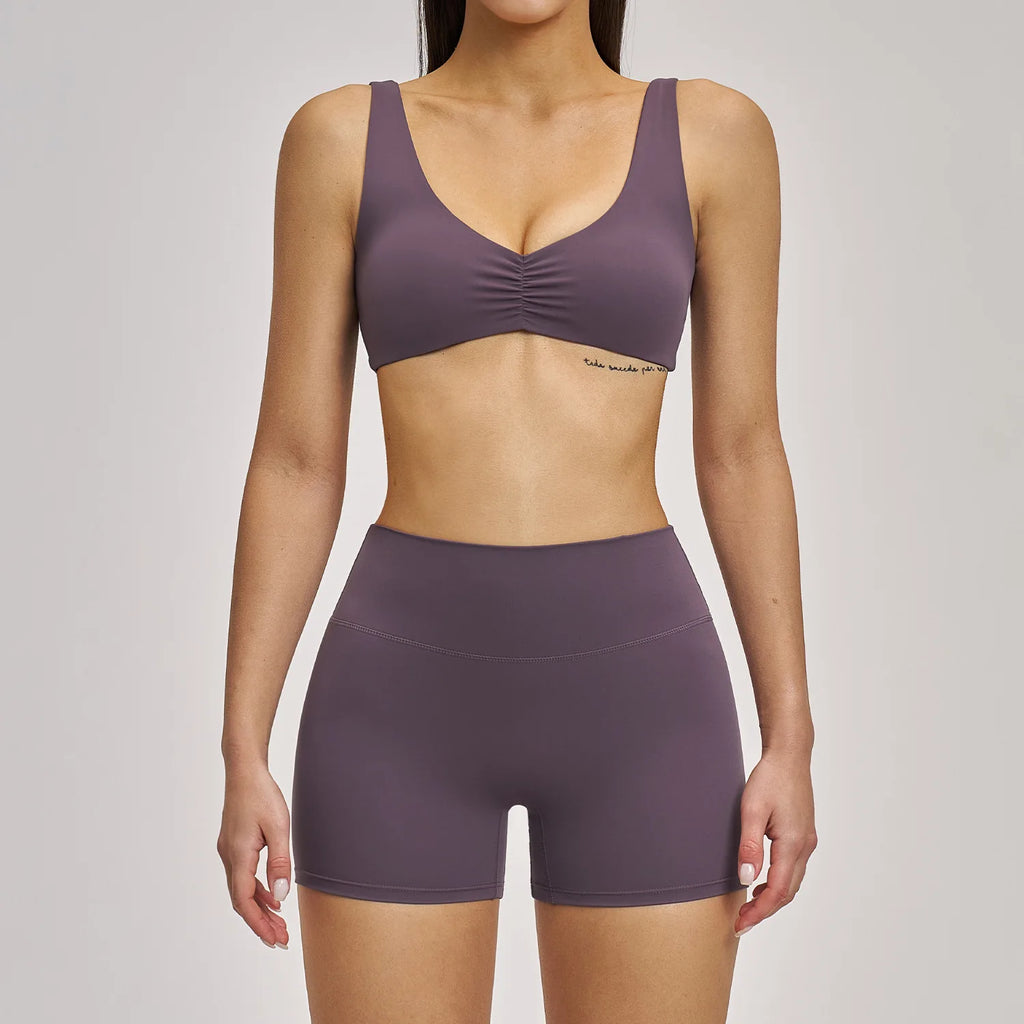 Person wearing a purple sports bra and shorts set on a plain background