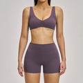 Person wearing a purple sports bra and shorts set on a plain background