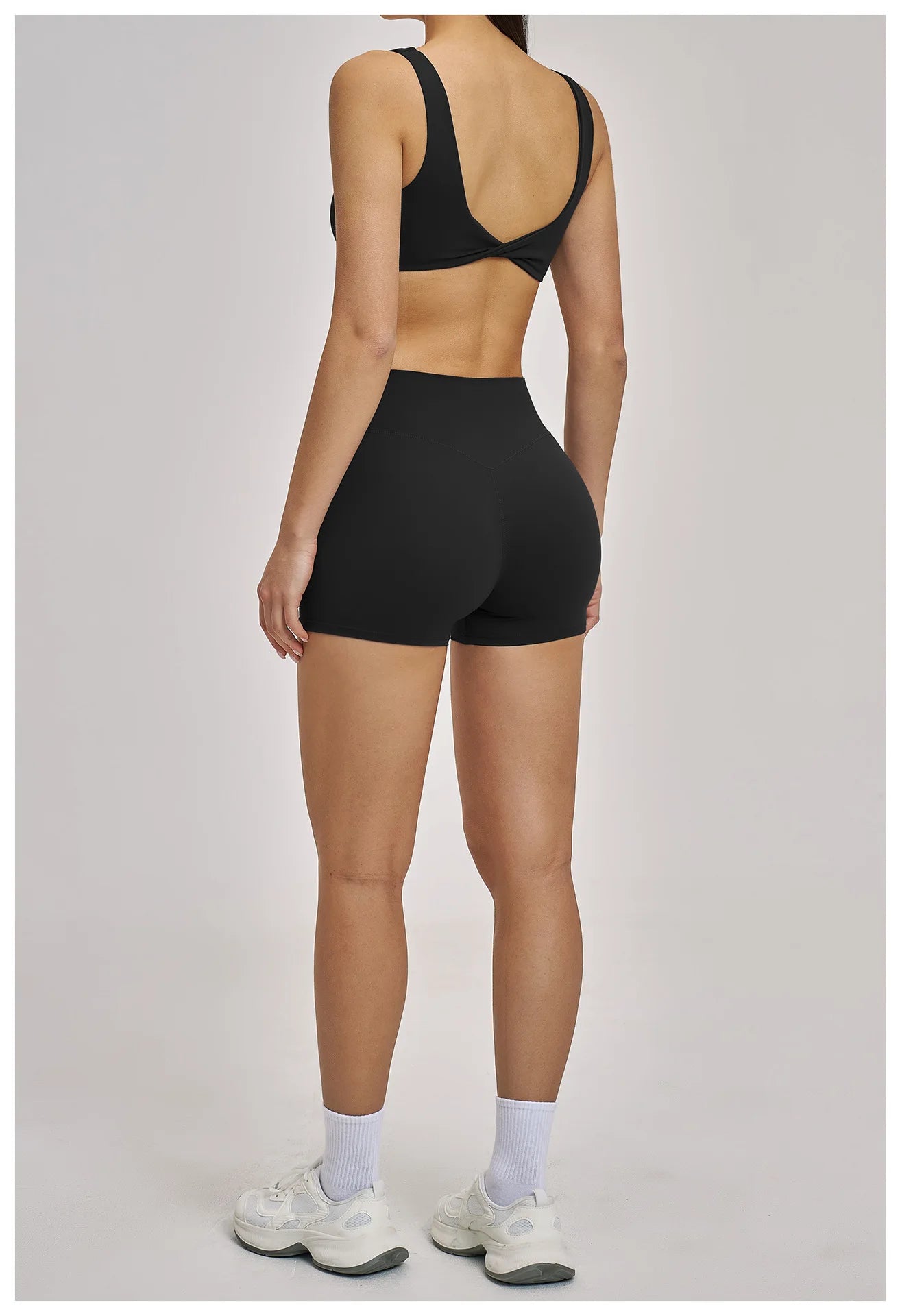 Person wearing a black sports bra and shorts on a plain background