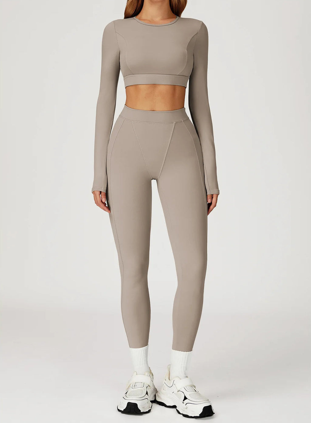 Person wearing a beige long-sleeve crop top and leggings set on a white background