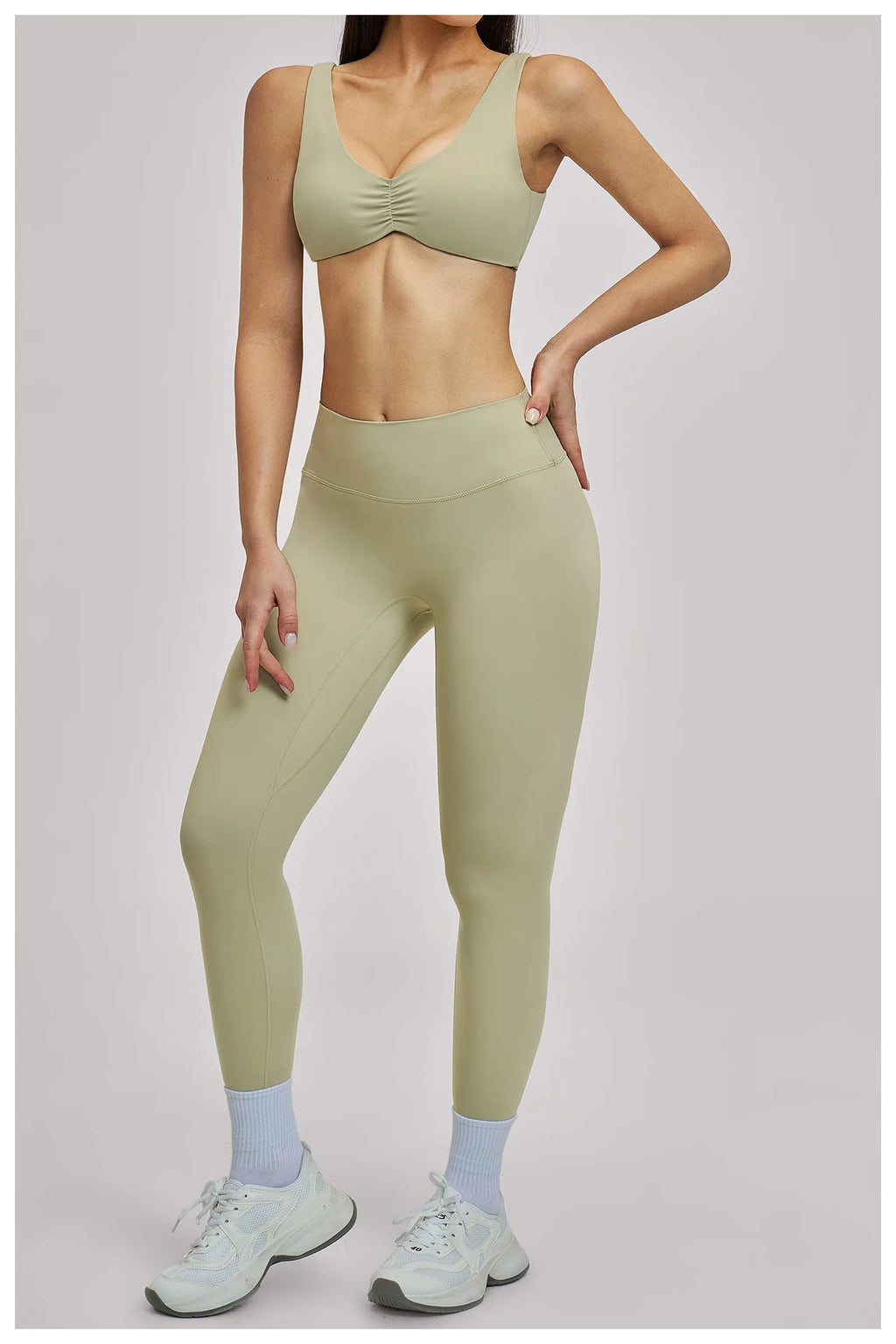 Person wearing a green sports bra and leggings set on a plain background