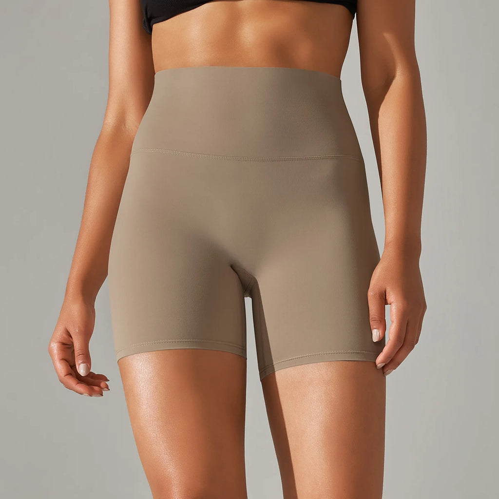 Person wearing beige high-waisted shorts on a neutral background