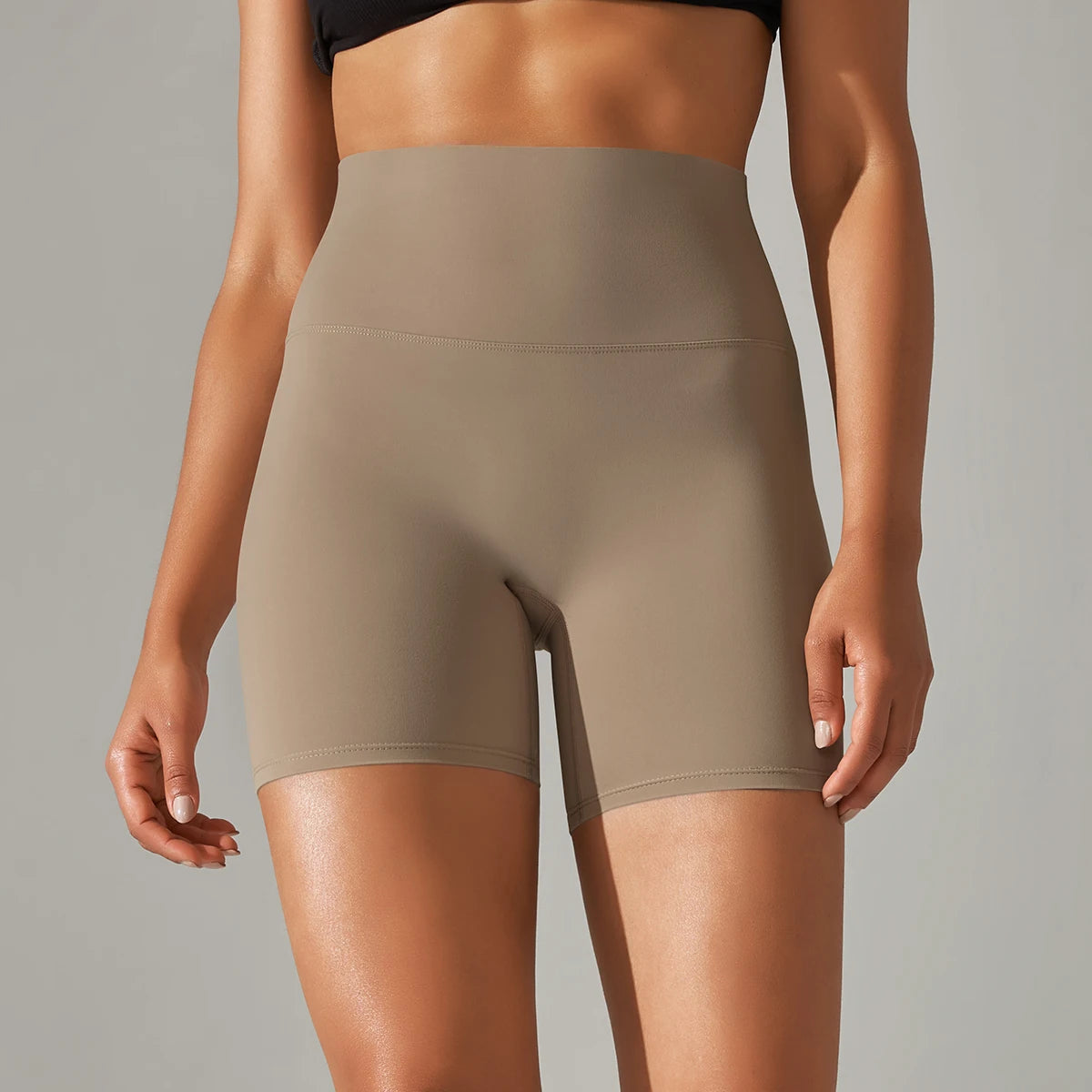 Person wearing beige high-waisted shorts on a neutral background