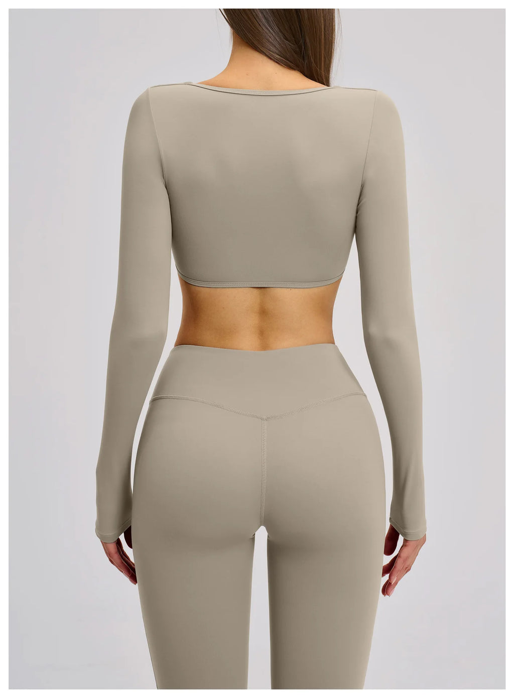 Person wearing a matching beige long-sleeve crop top and leggings set on a light gray background