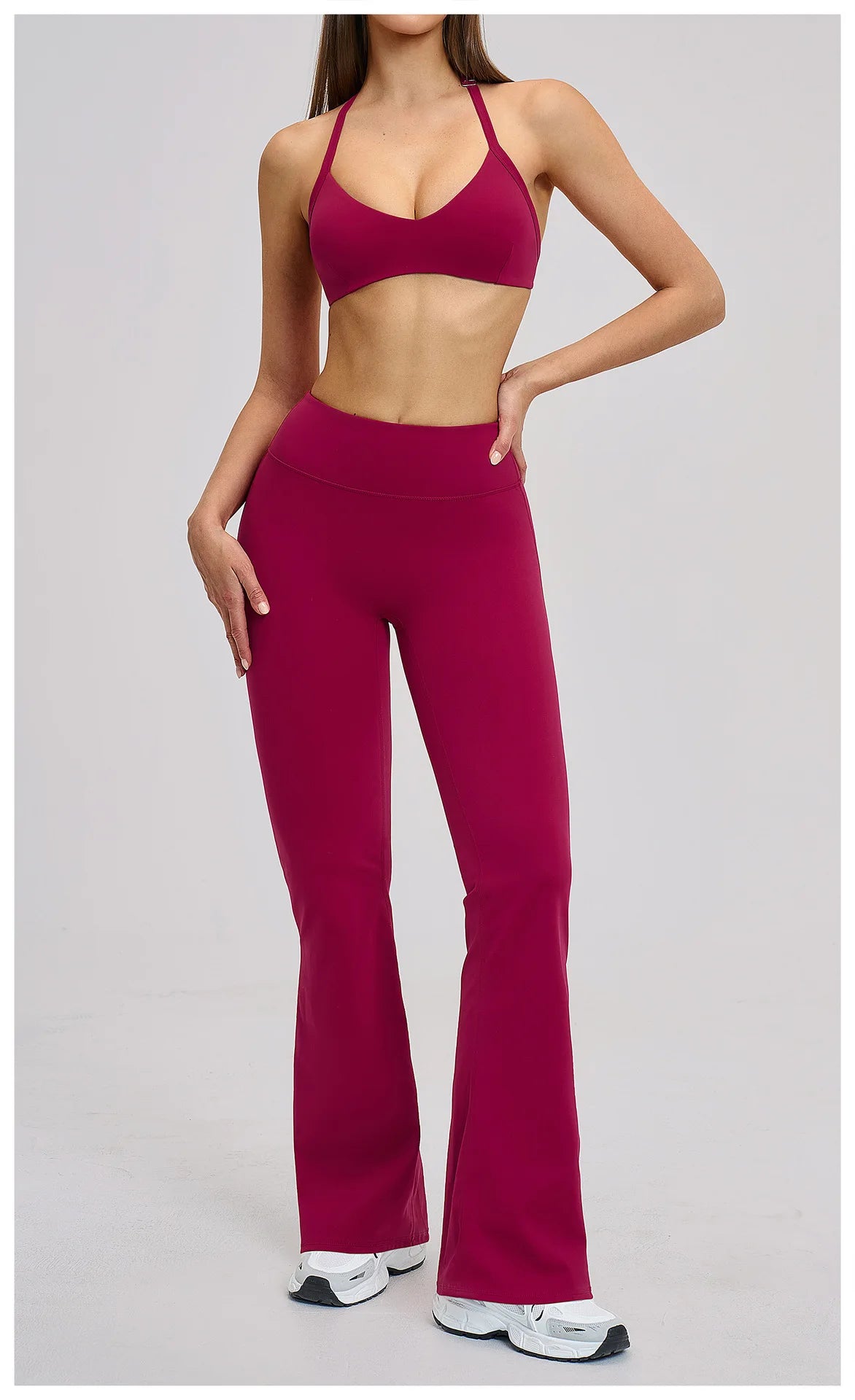 Person wearing a maroon sports bra and leggings set on a light gray background