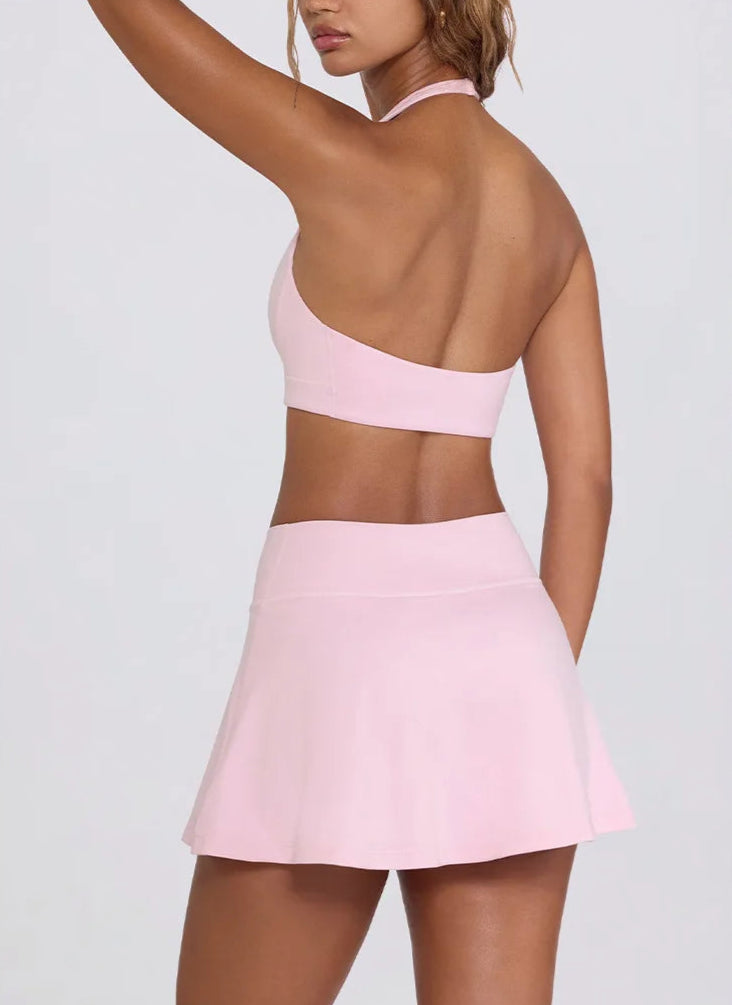 Person wearing a pink open-back top and skirt on a white background