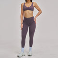 Person wearing a purple sports bra and leggings set on a plain background