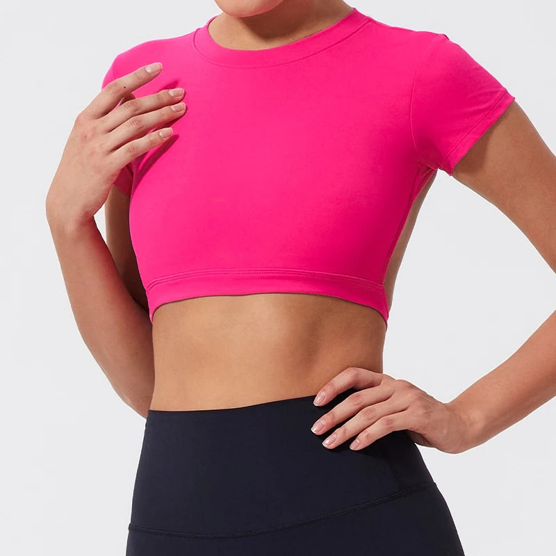 Person wearing a bright pink crop top and black leggings on a light gray background
