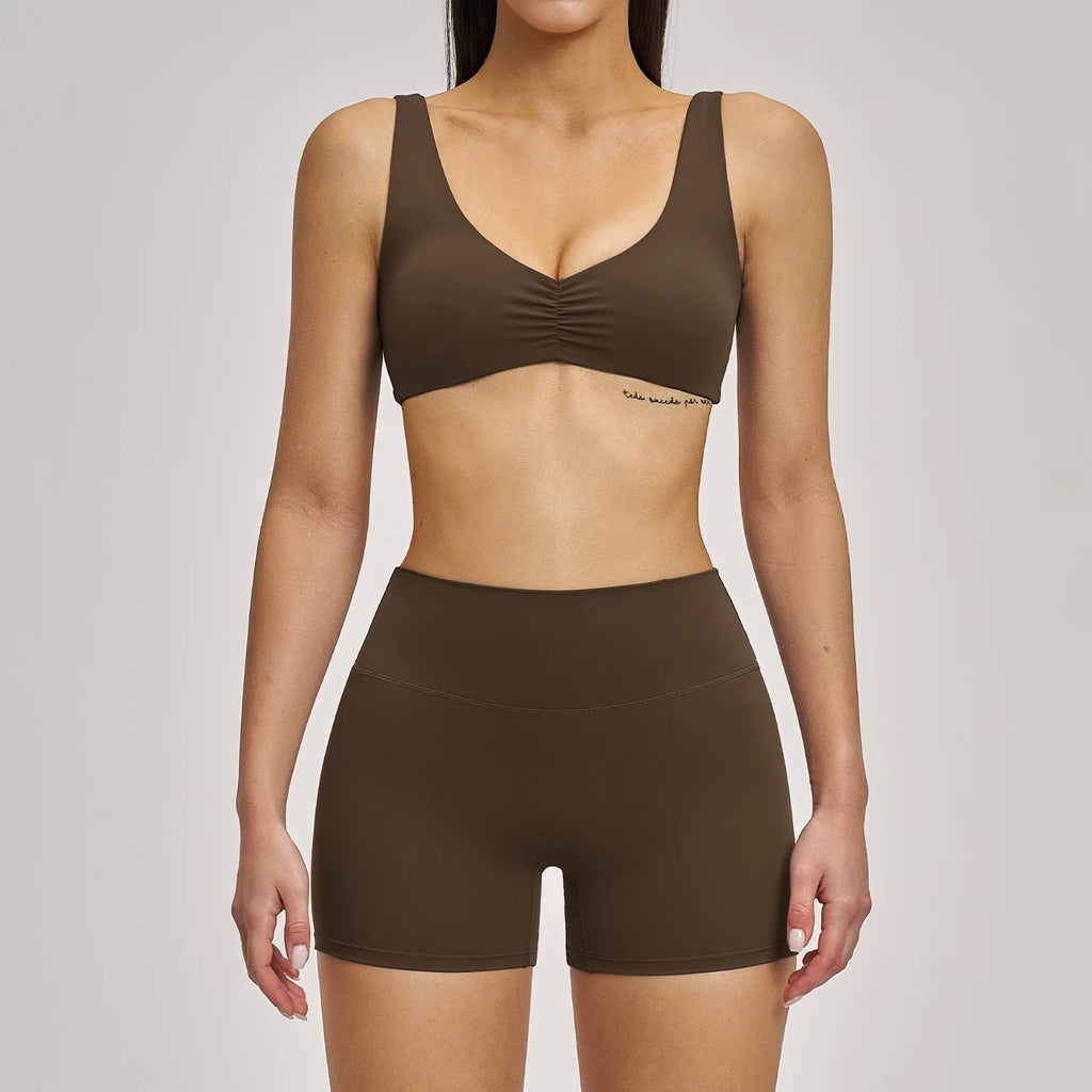 Person wearing a brown sports bra and shorts set on a plain background