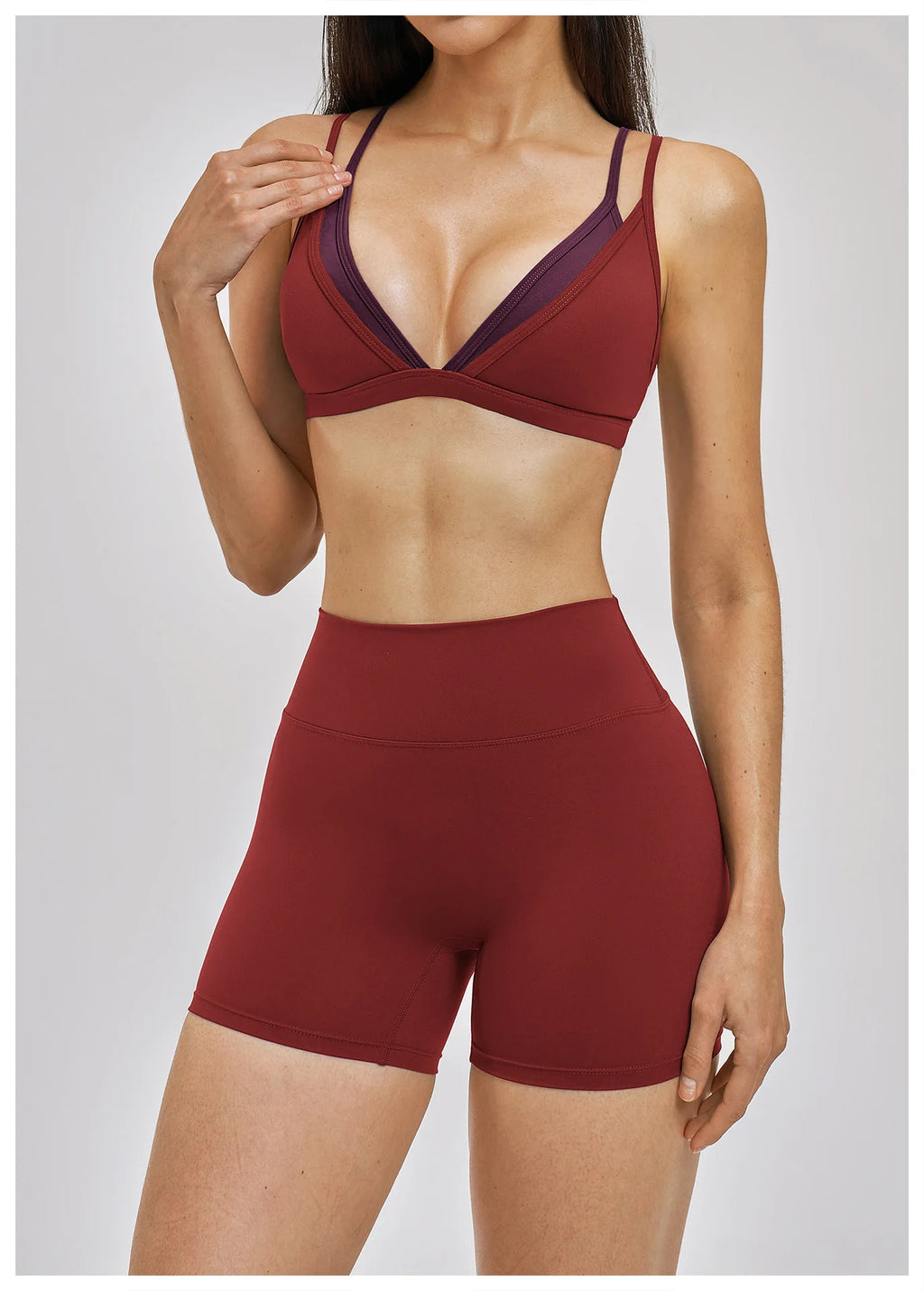 Person wearing a maroon sports bra and shorts on a plain background