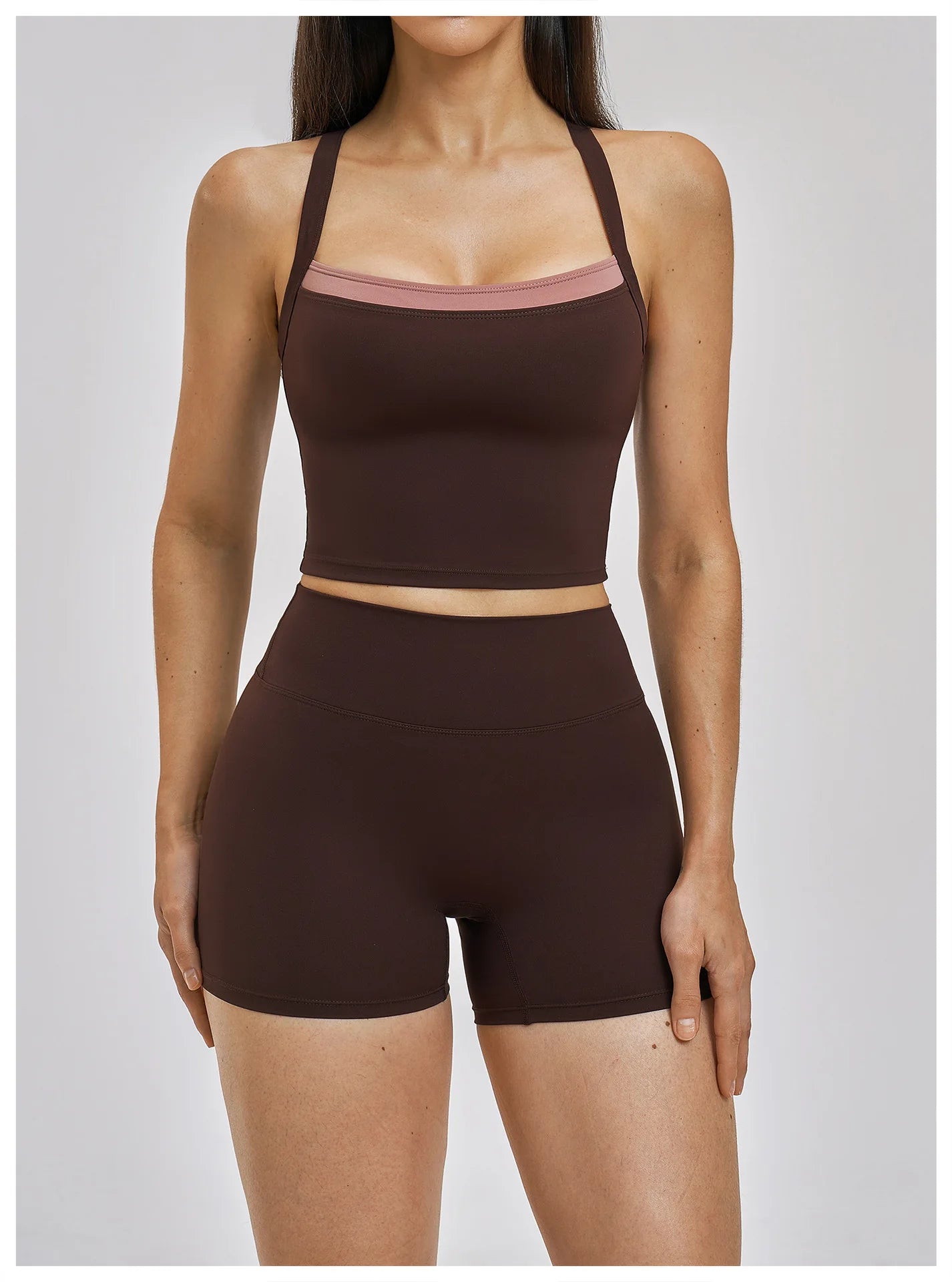 Person wearing a brown sports bra and shorts set on a plain background