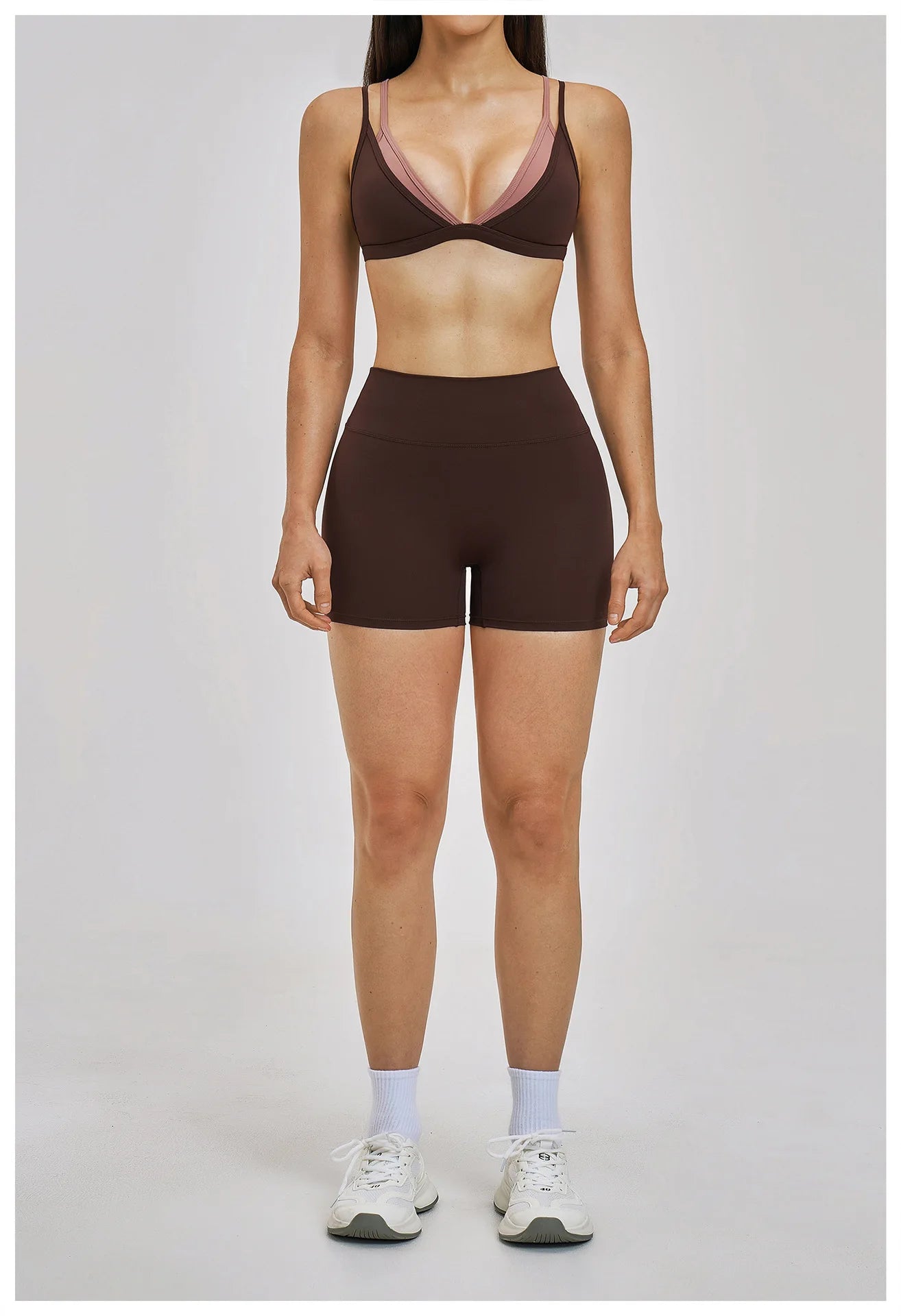 Person wearing a brown sports bra and shorts set on a plain background