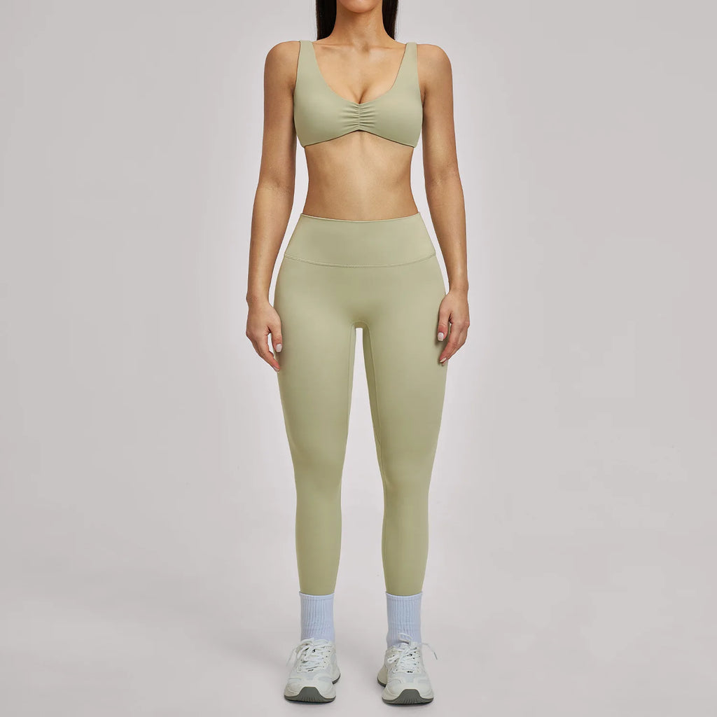Person wearing a green sports bra and leggings set on a gray background
