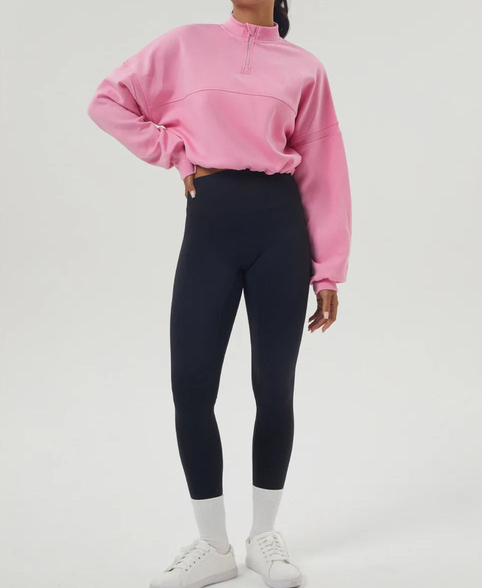 Person wearing a pink sweatshirt and black leggings on a white background