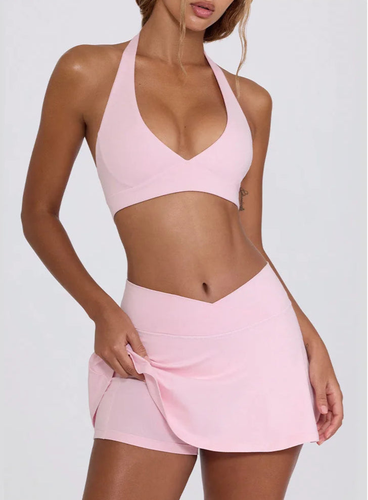 Woman wearing a pink sports bra and skirt set on a white background