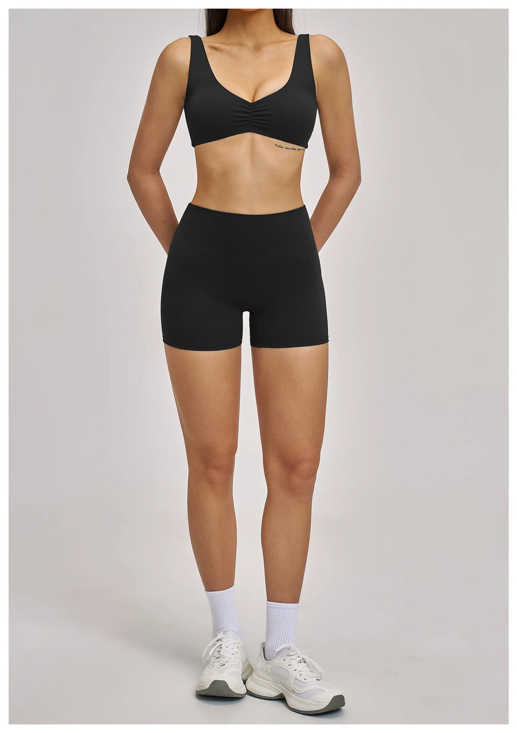 Person wearing a black sports bra and shorts on a gray background