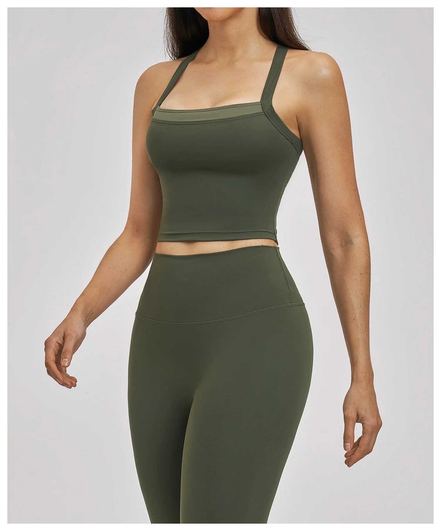 Person wearing a green sports bra and leggings set on a light gray background