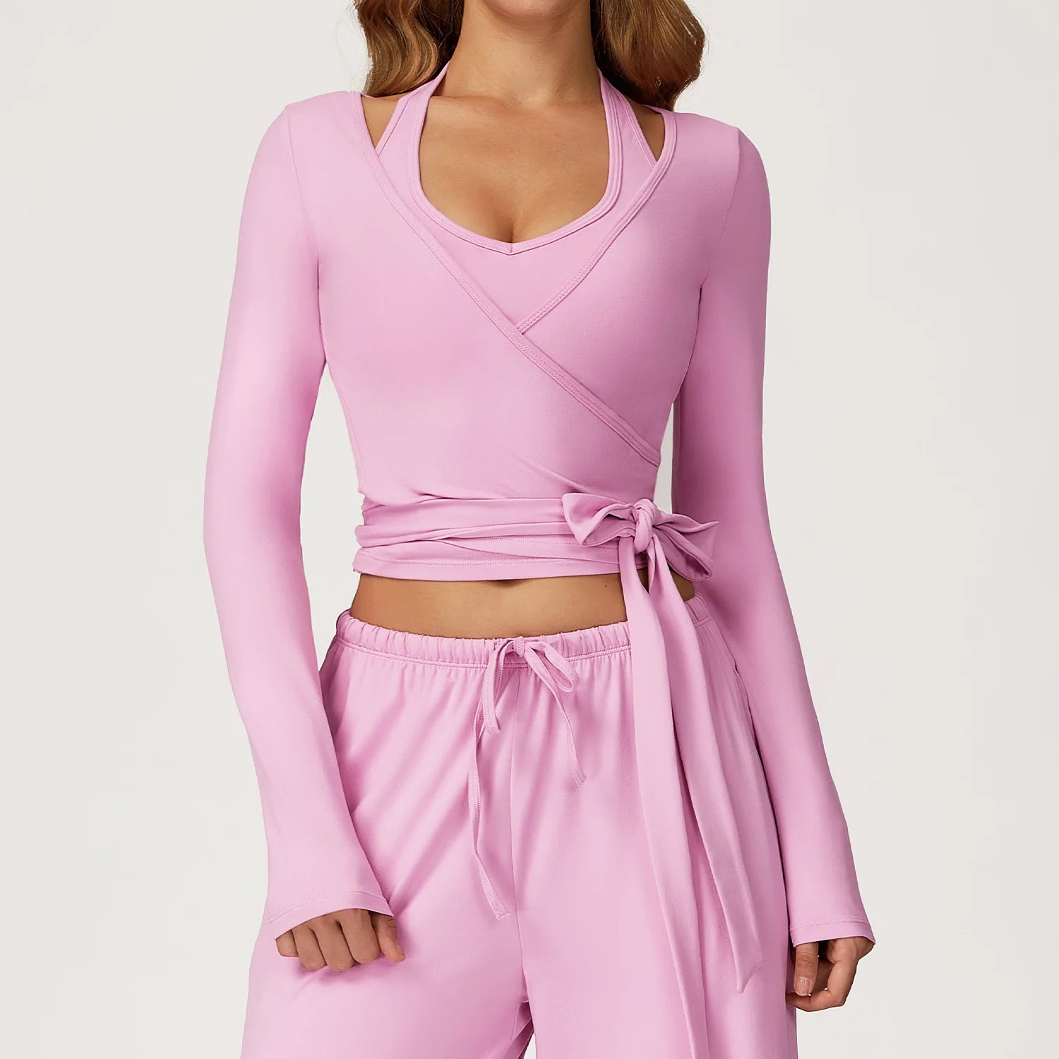 Pink long-sleeve ballet wrap top and pants set on a plain background
