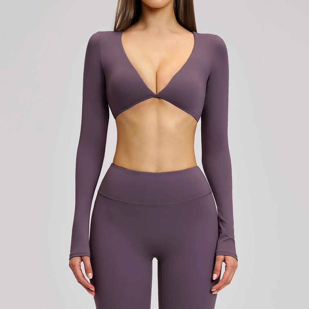 Purple athletic outfit with long sleeves and a deep neckline on a gray background