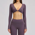 Purple athletic outfit with long sleeves and a deep neckline on a gray background