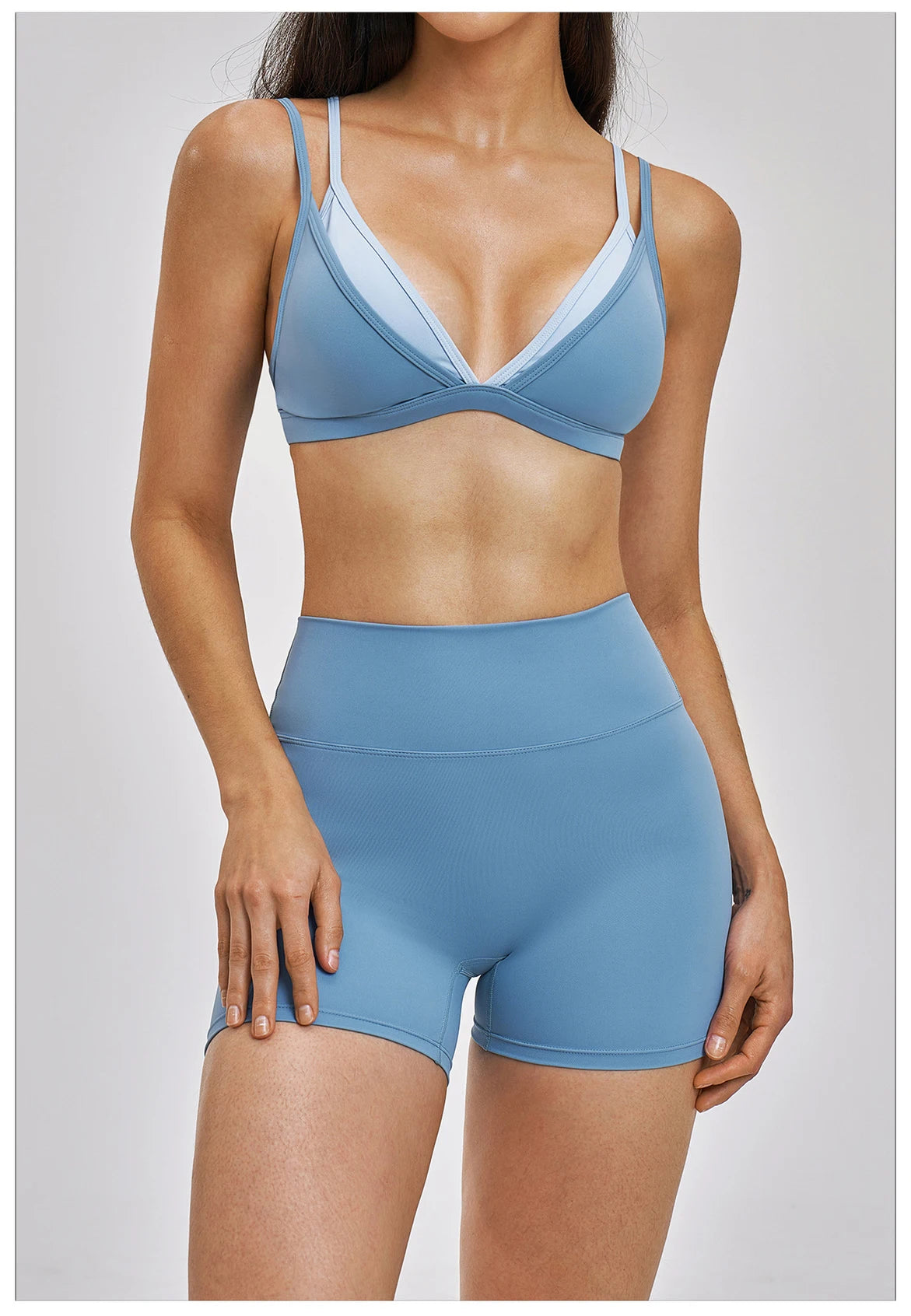 Woman wearing a blue sports bra and shorts set on a white background