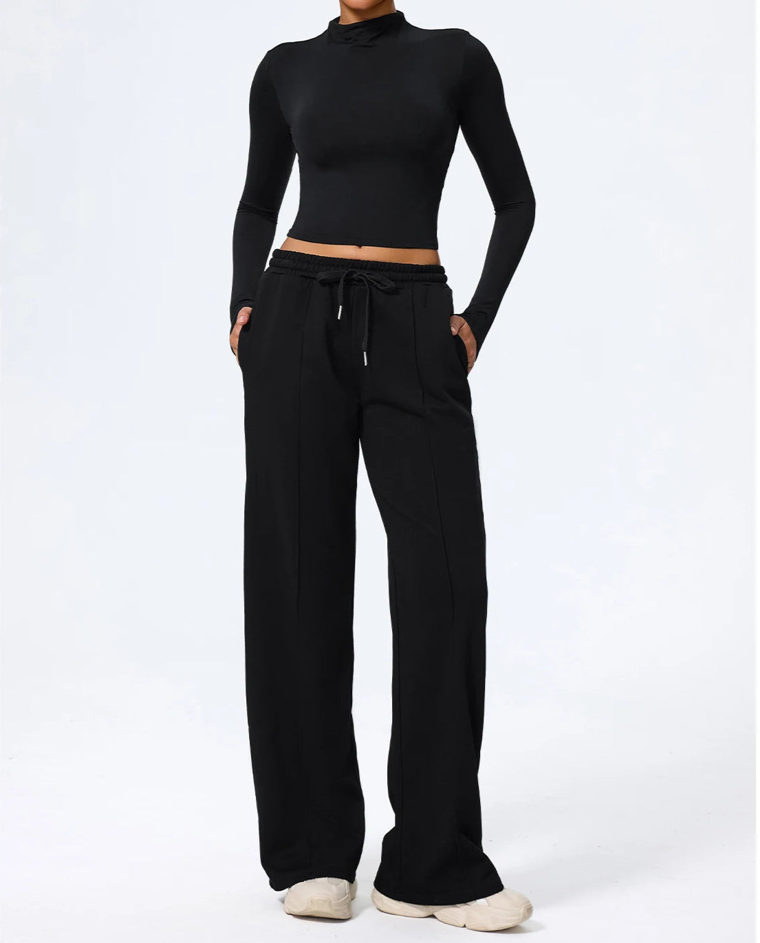 Person wearing a black long-sleeve crop top and wide-leg pants on a white background