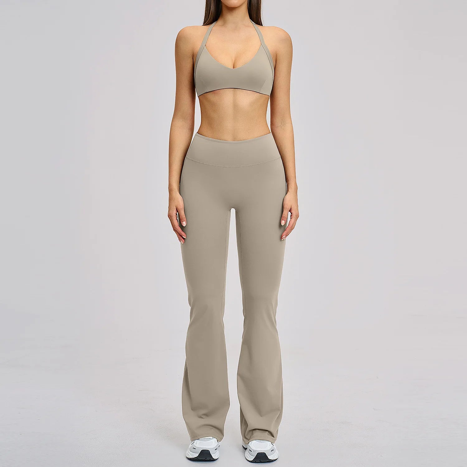 Person wearing a beige sports bra and leggings set on a gray background