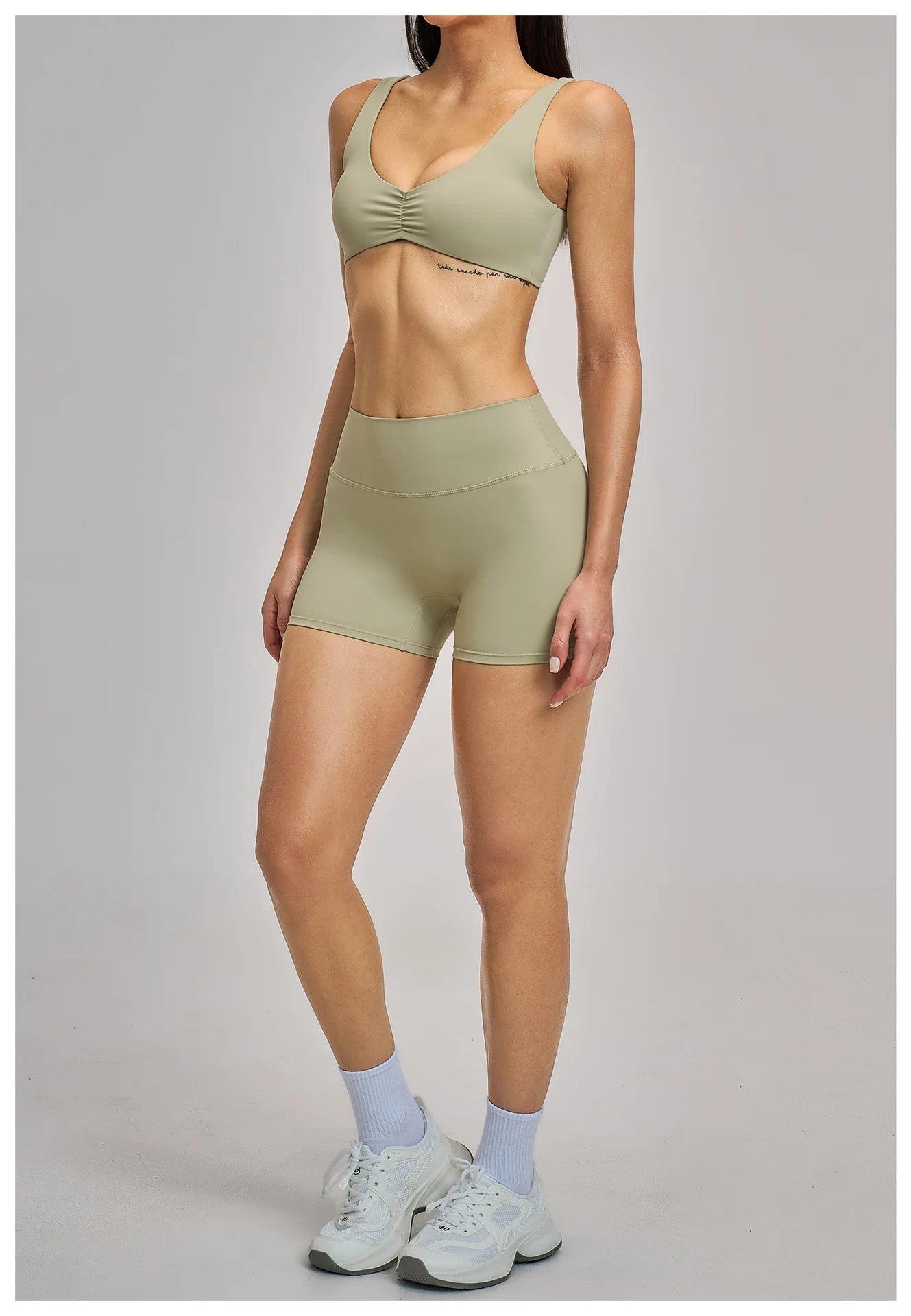 Person wearing a green sports bra and shorts set on a gray background