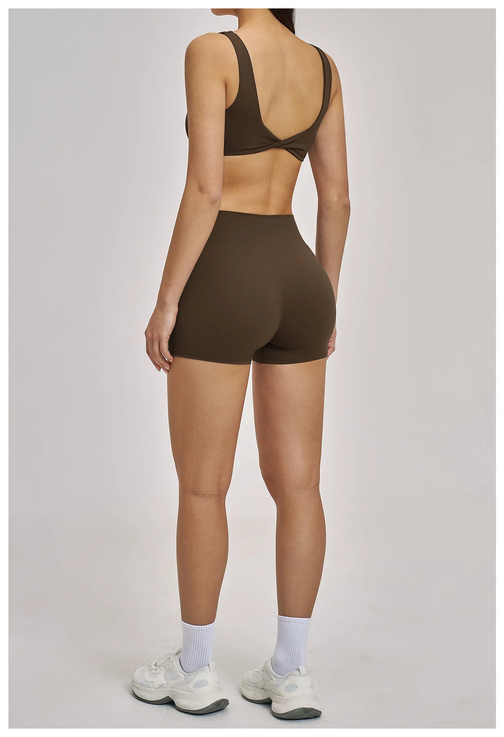 Person wearing a brown sports bra and shorts set on a plain background