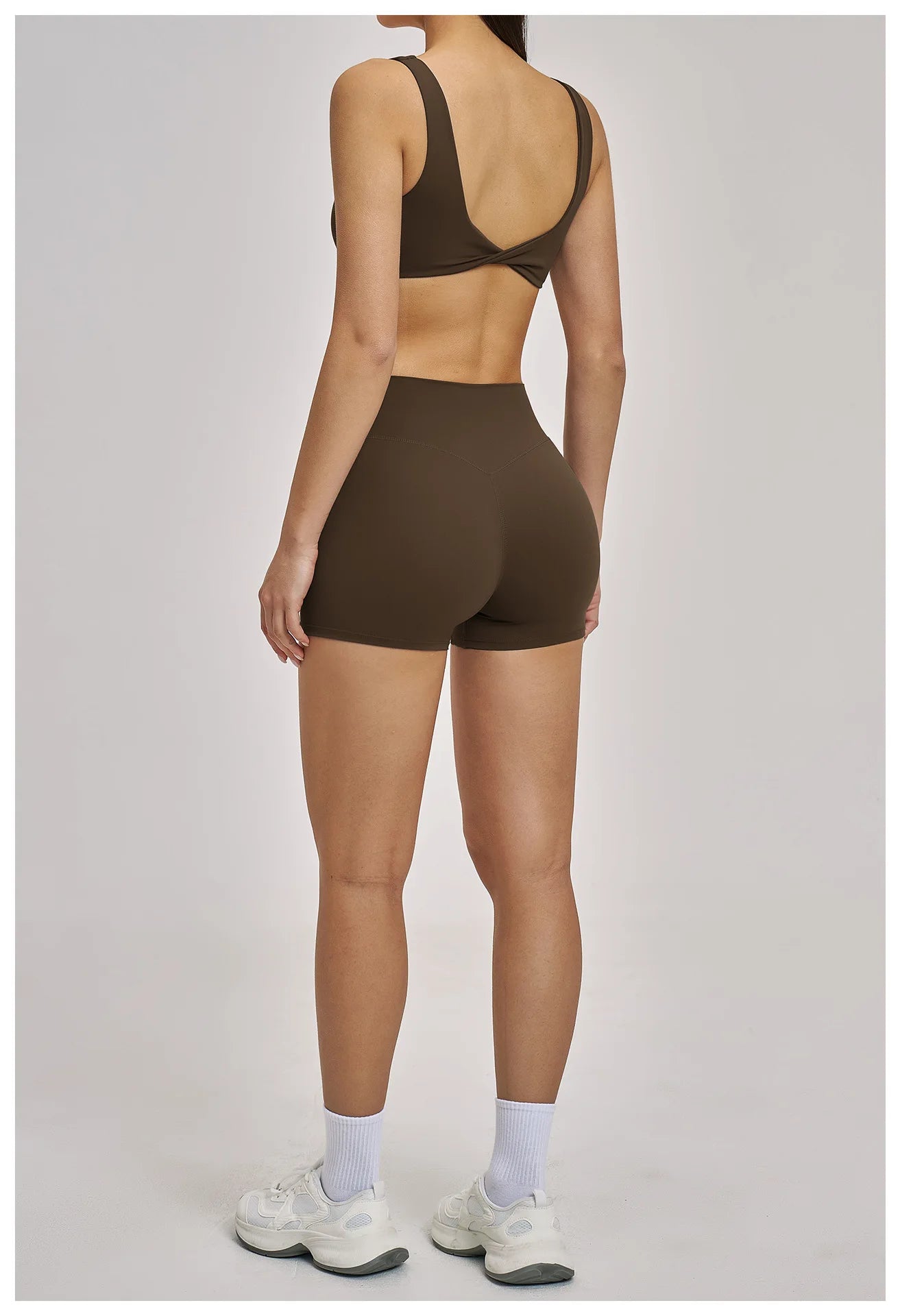 Person wearing a brown sports bra and shorts set on a plain background