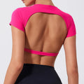 Person wearing a pink open-back top on a plain background