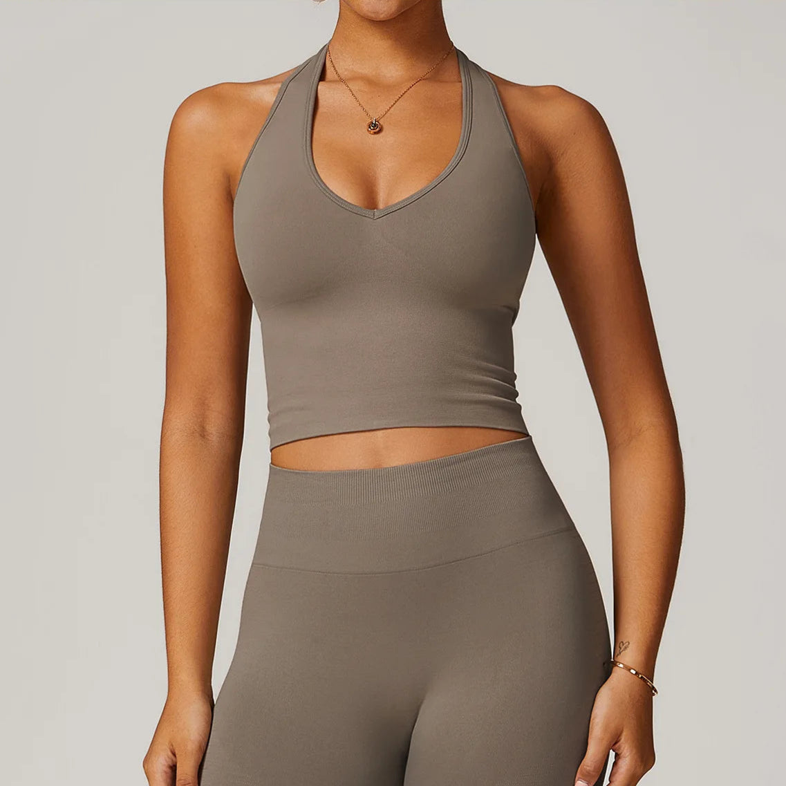 Person wearing a brown sports bra and leggings set on a plain background