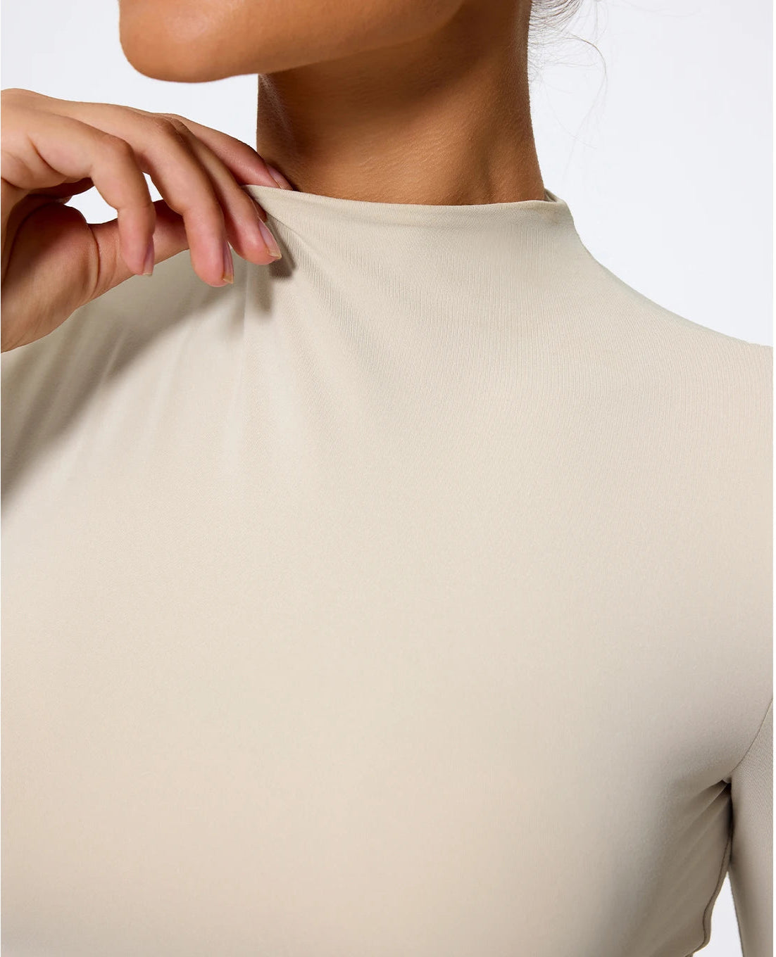 Close-up of a beige long-sleeve top on a plain background