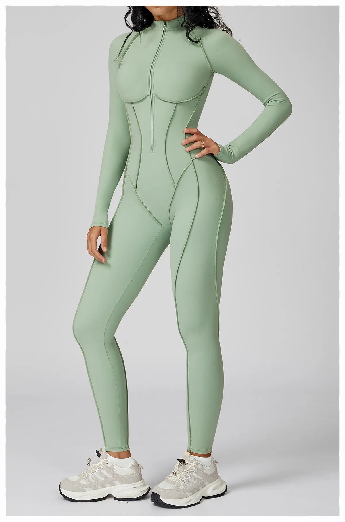 Woman wearing a pastel green sports longsleeve bodysuit on a gray background