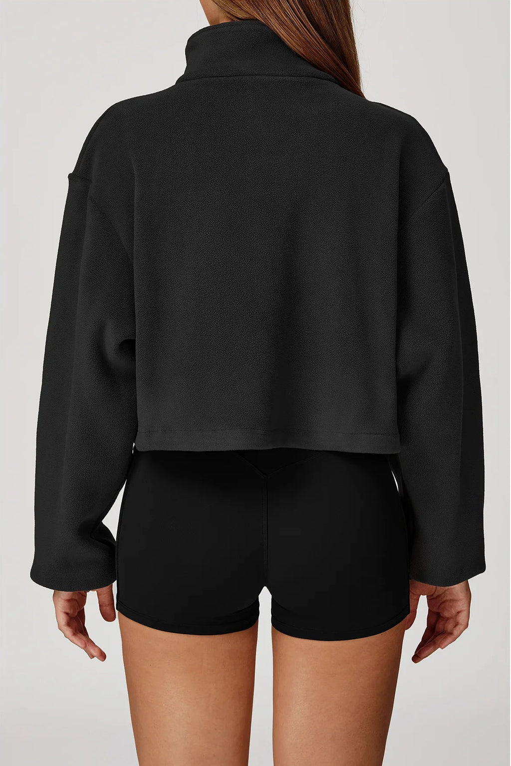 Woman wearing a plush black jacket and shorts on a white background