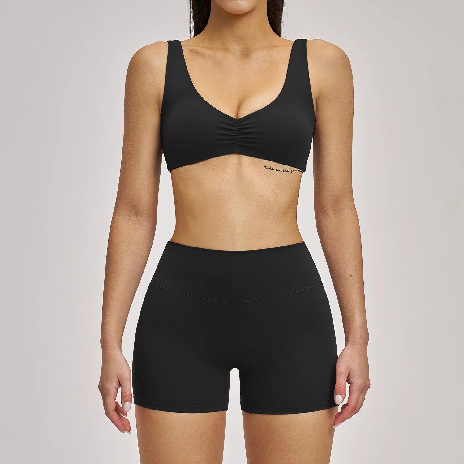 Person wearing a black sports bra and shorts set on a plain background