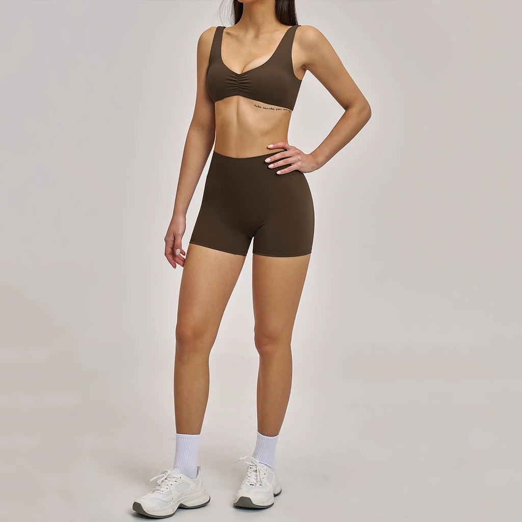 Person wearing a brown sports bra and shorts set on a plain background