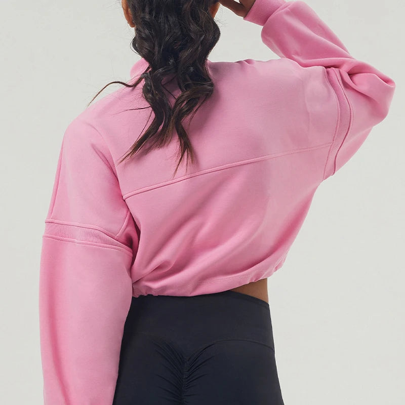 Person wearing a pink sweatshirt and black leggings on a light gray background