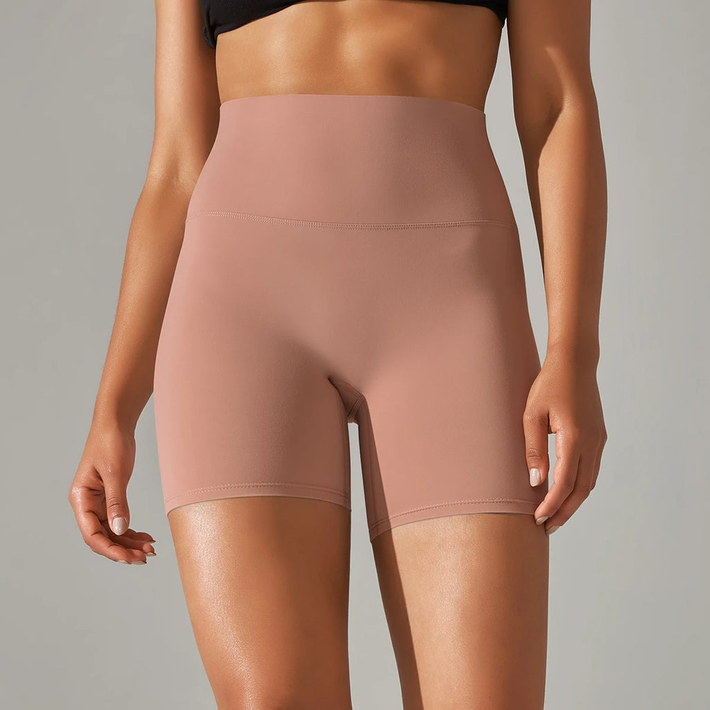 Person wearing a pair of sand clay high-waisted shorts on a neutral background