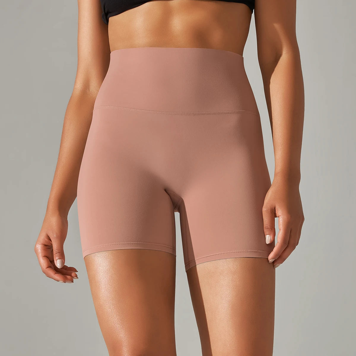 Person wearing a pair of sand clay high-waisted shorts on a neutral background