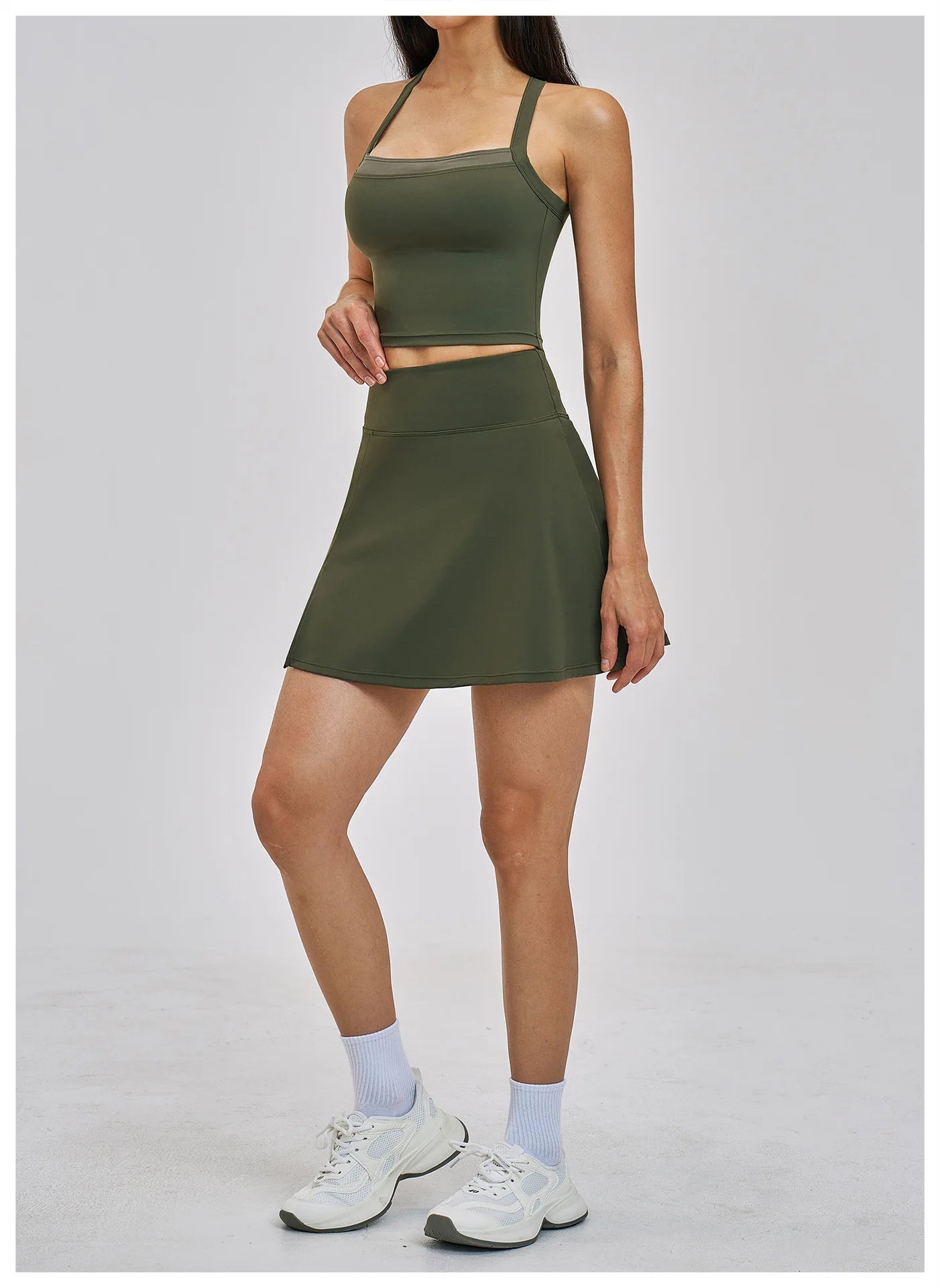 Person wearing a green athletic outfit with a skirt on a white background