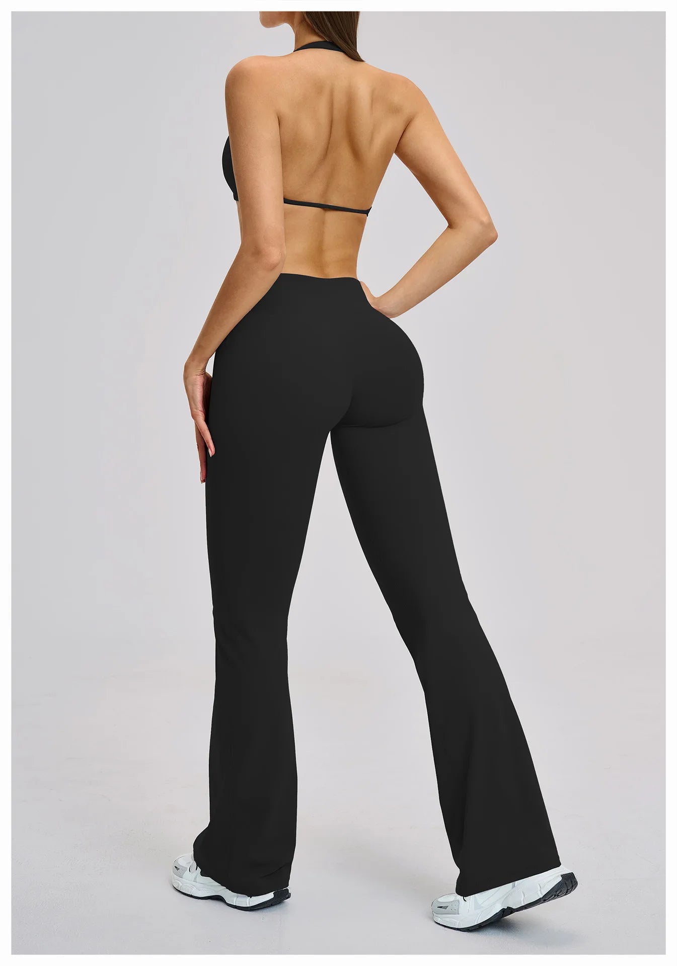 Person wearing black high-waisted pants on a light gray background