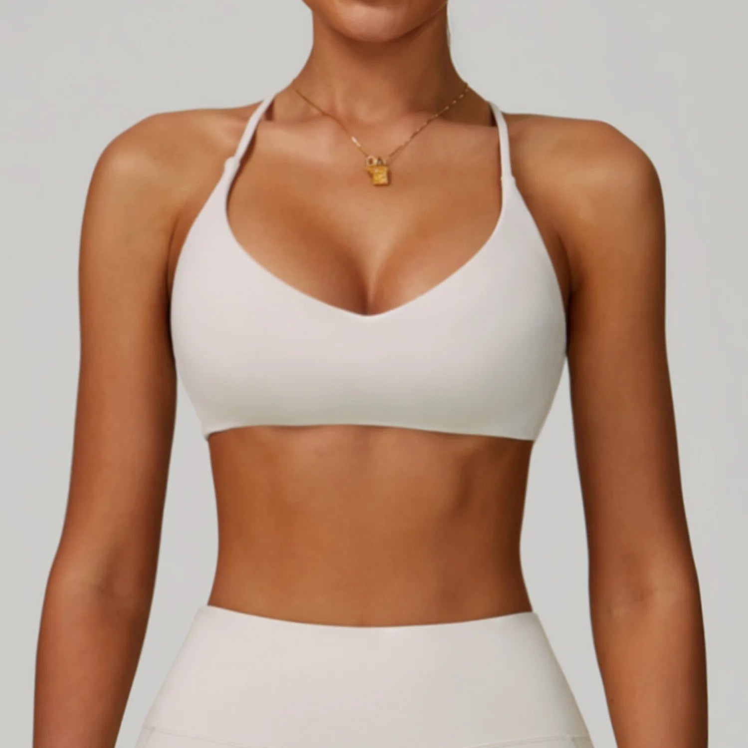 Person wearing a white sports bra and leggings on a plain background