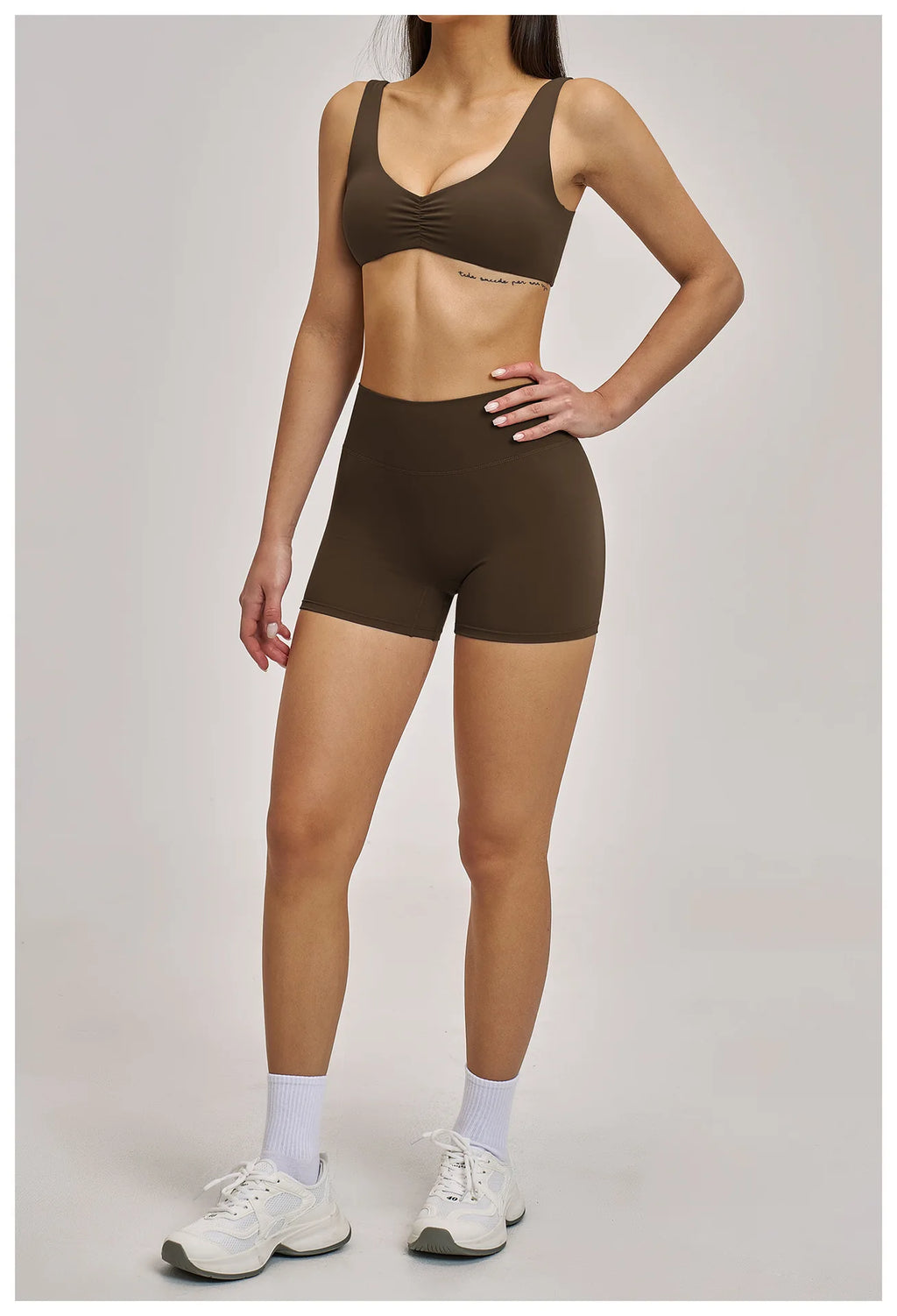 Person wearing a brown sports bra and shorts set on a plain background
