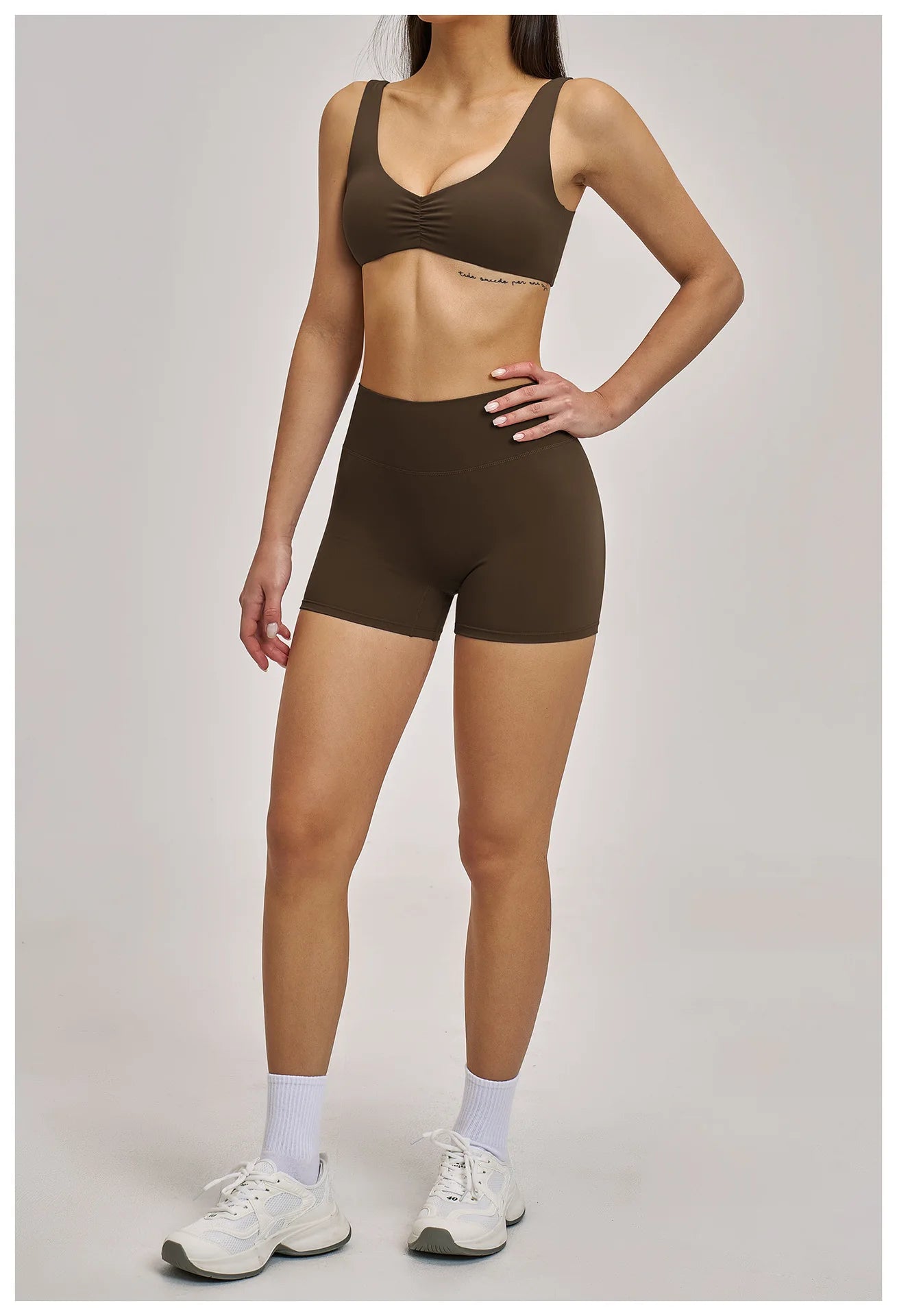 Person wearing a brown sports bra and shorts set on a plain background