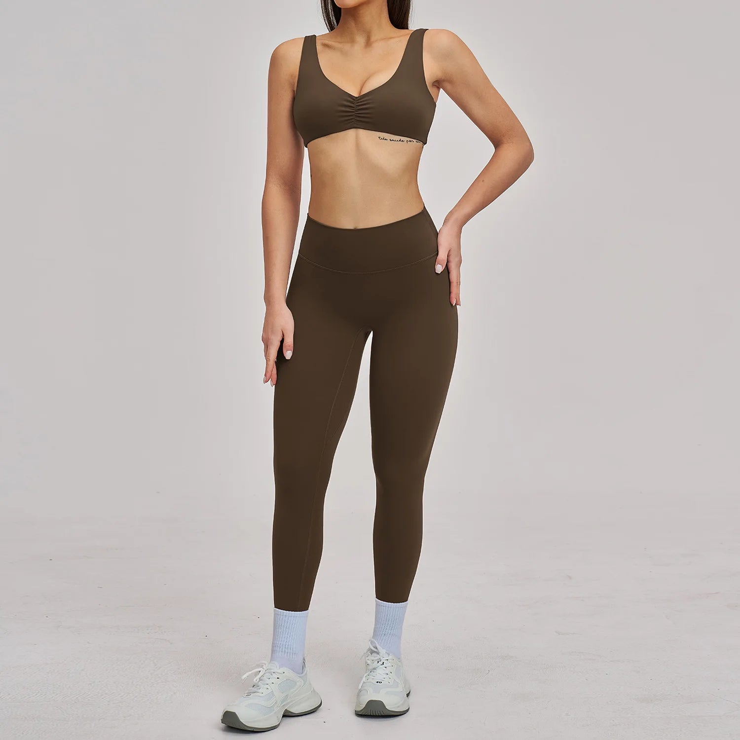 Person wearing a brown sports bra and leggings set on a gray background