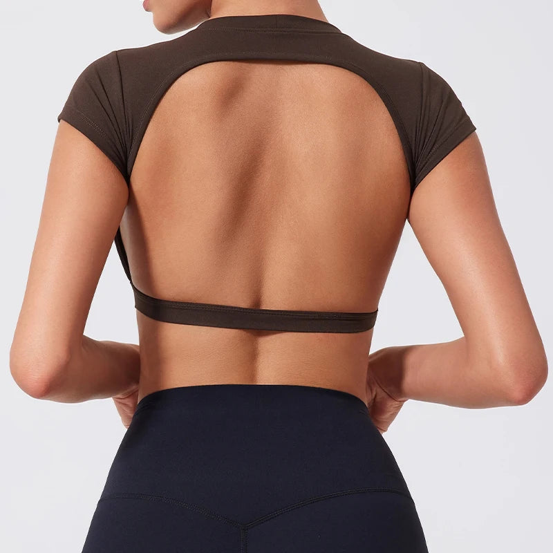 Person wearing a brown open-back top and black leggings on a light gray background